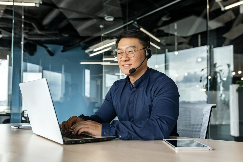 Happy and smiling worker with headset for video call, Asian tech support man talking to online